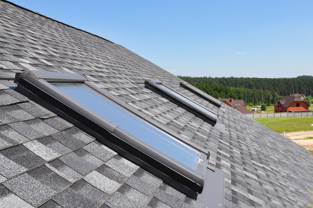 Attic skylight. Asphalt shingled house. Arlington Roofing construction with attic, roof, windows, skylights, and waterproofing.