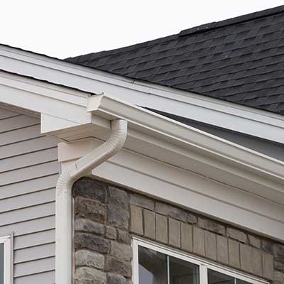 Close up of a white, k-style gutter system with a downsprout